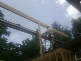 Carpenter setting a ridge beam over a new addition frame — Ice Dam Removal by Roofing Brothers in Star City