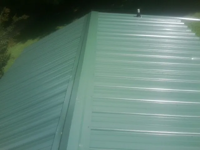New green metal panels meeting at the ridge of a roof — Flat Roof Repair work by our crew in Star City