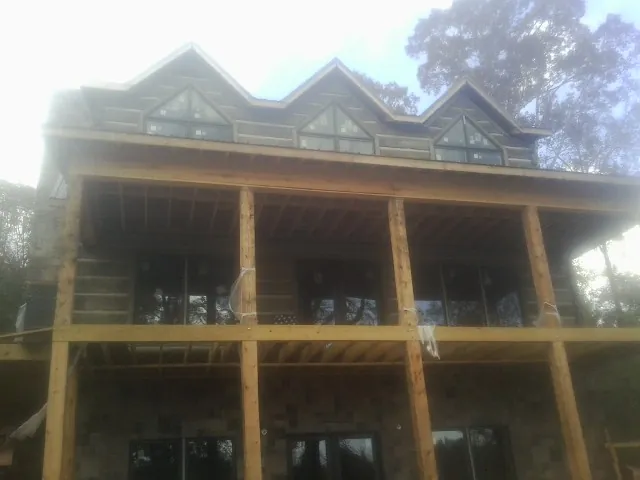 Dormers and porch framing on a large log home under construction — Roof Coating work by our crew in Star City