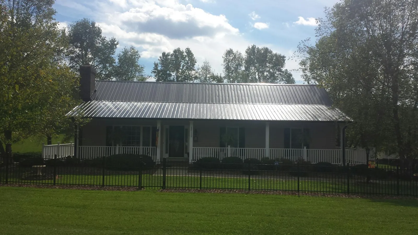 Gray metal roof on a brick ranch with a full width front porch — Gutter Guard Installation work by our crew in Star City