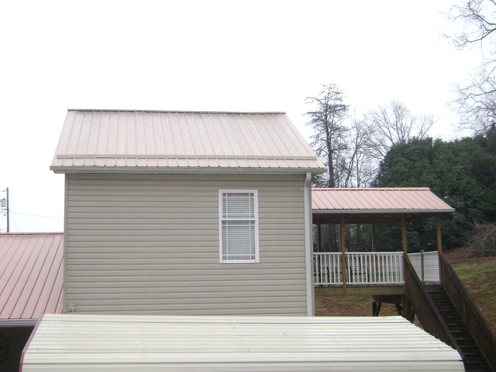 Tan metal roofs on a two story addition and attached porch, from a Roof Replacement job in Star City