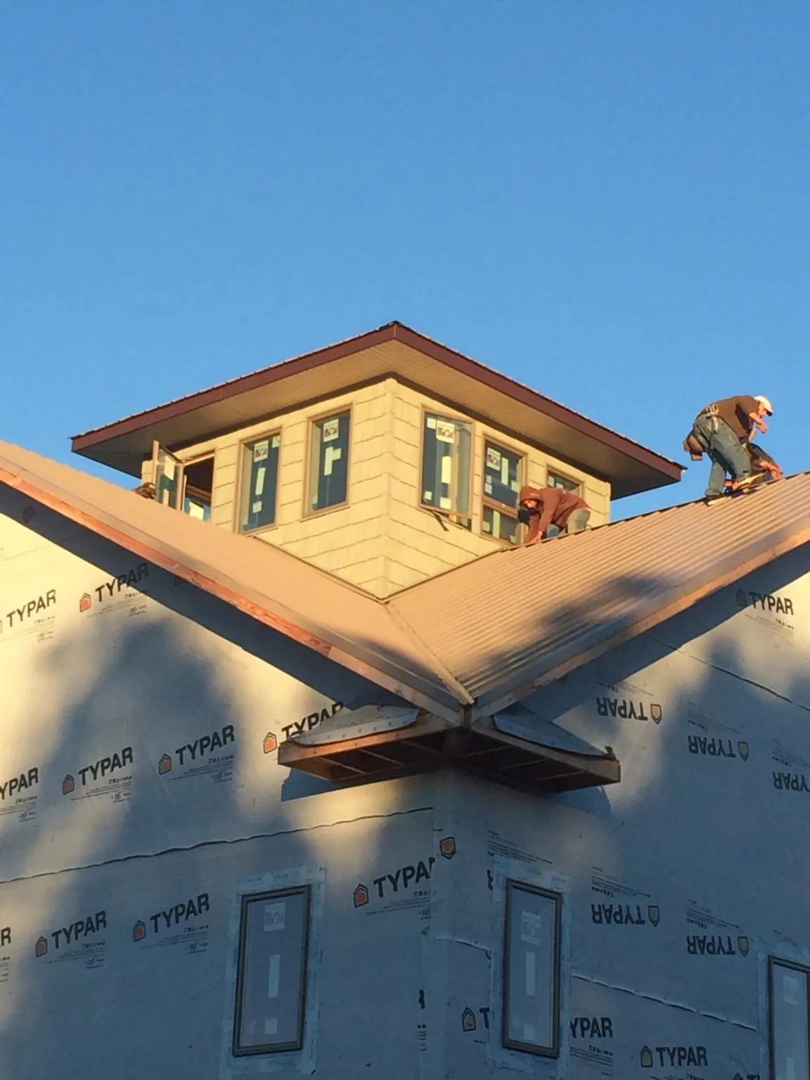 Roofers working around a rooftop cupola on a new metal roof at sunset — Roof Waterproofing in Star City by Roofing Brothers